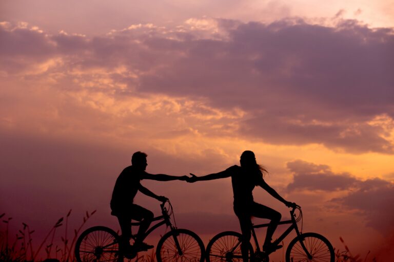 Situations-woman-on-bike-reaching-for-man's-hand-behind-her-also-on-bike.jpg